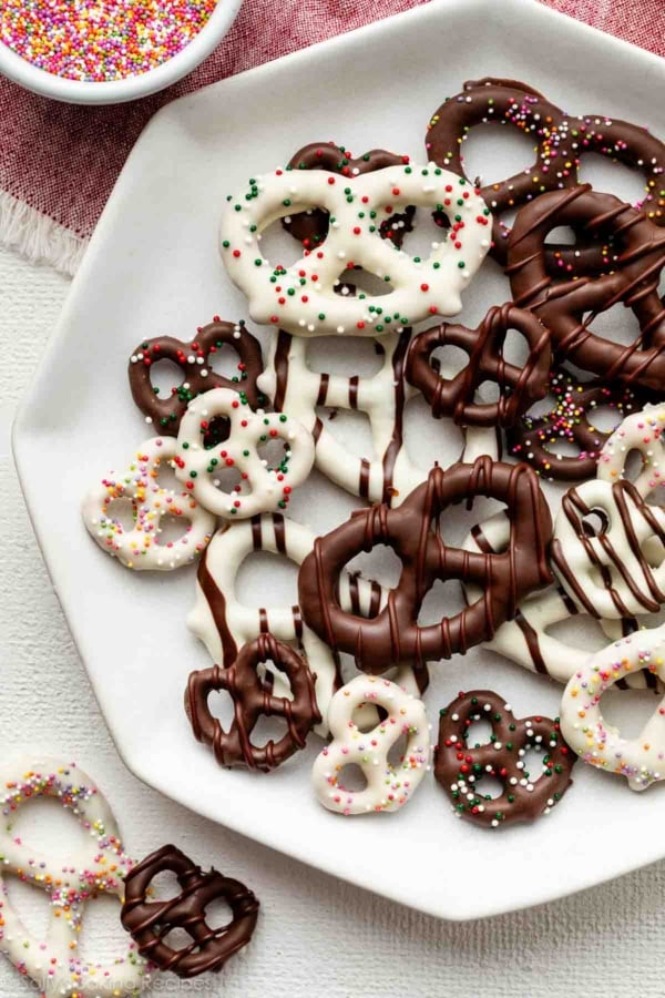 plate of various chocolate covered pretzels including some with white chocolate, chocolate drizzles, and sprinkles.