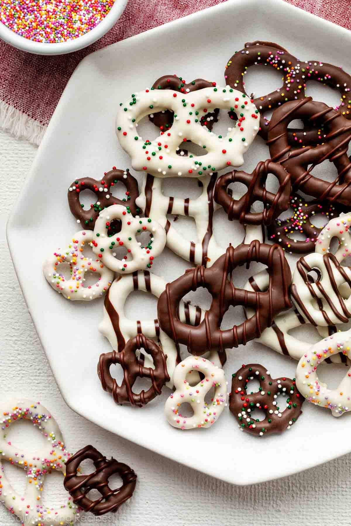 plate of various chocolate covered pretzels including some with white chocolate, chocolate drizzles, and sprinkles.