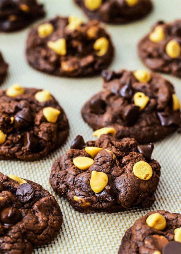 chocolate cookies with chocolate chips and peanut butter chips on a silpat baking mat