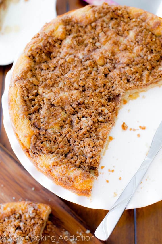 overhead image of super crumb coffee cake on a white cake stand with a few slices removed