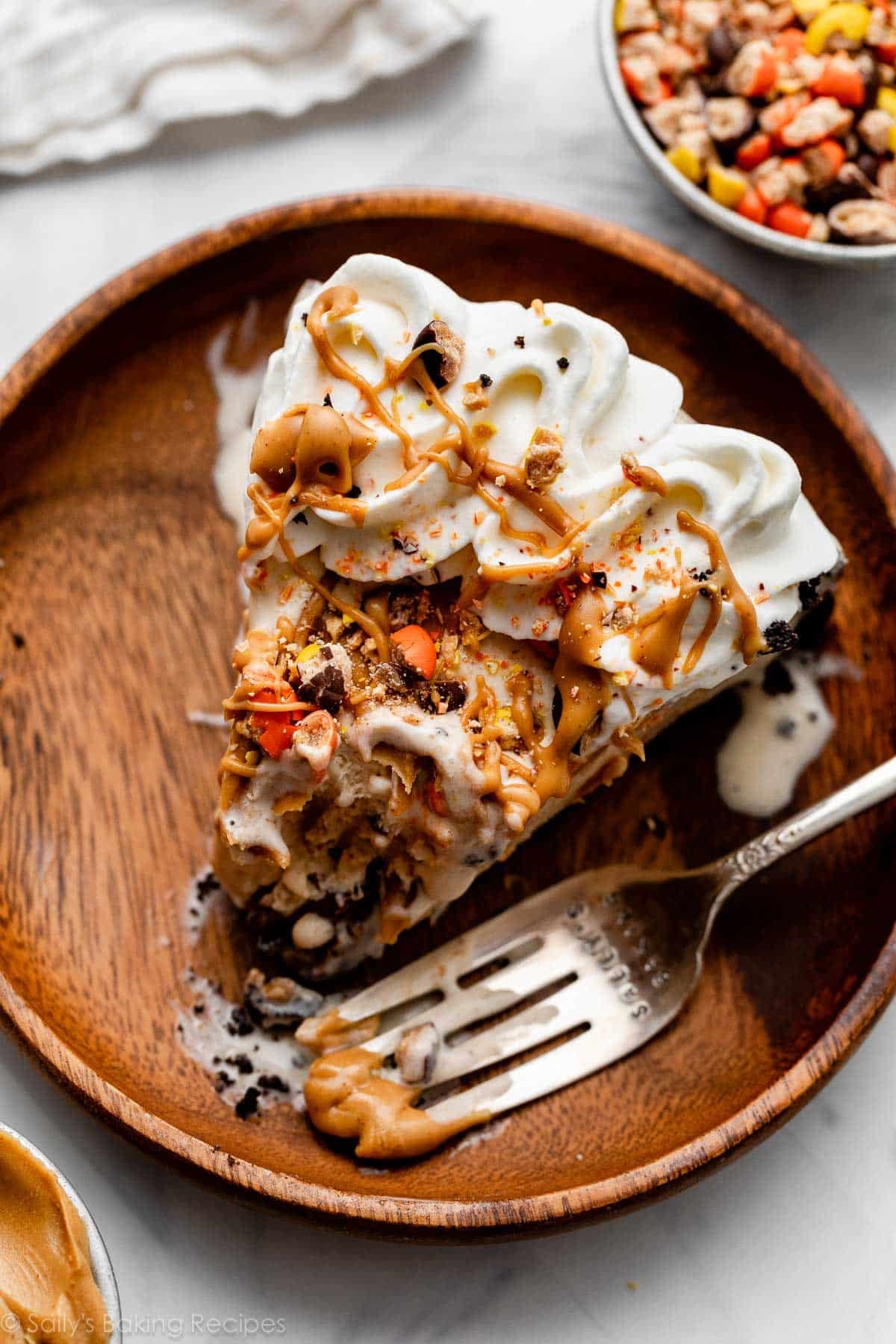 slice of peanut butter ice cream pie with bite taken out on wooden plate.
