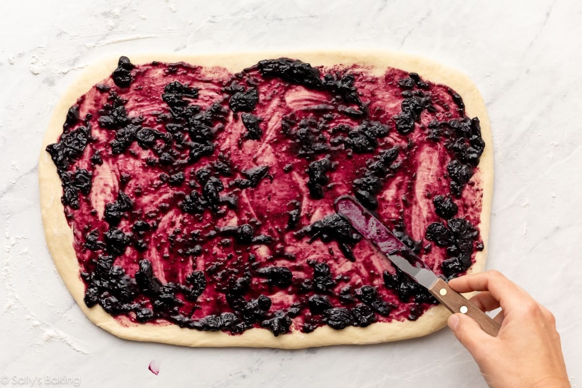spreading blueberry filling on rolled-out dough.