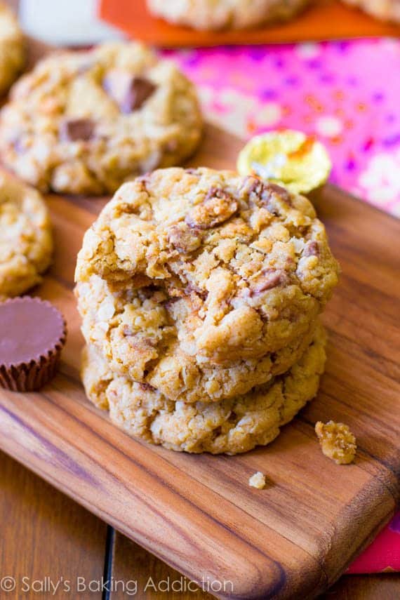 stack of peanut butter cup oatmeal cookies on a wood board with a bite taken out of one