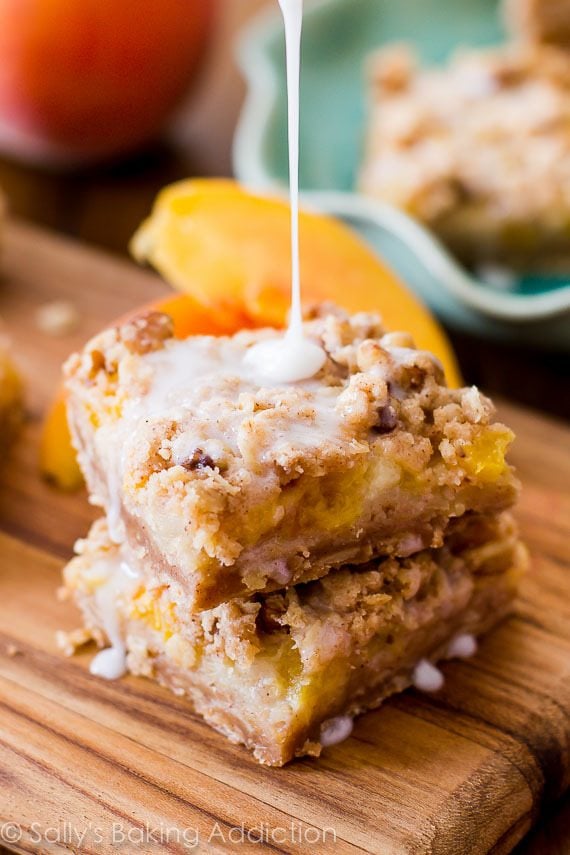 drizzling vanilla icing onto stack of peaches and cream bars