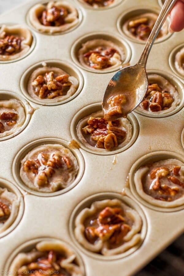spooning pecan filling into mini muffin crusts.