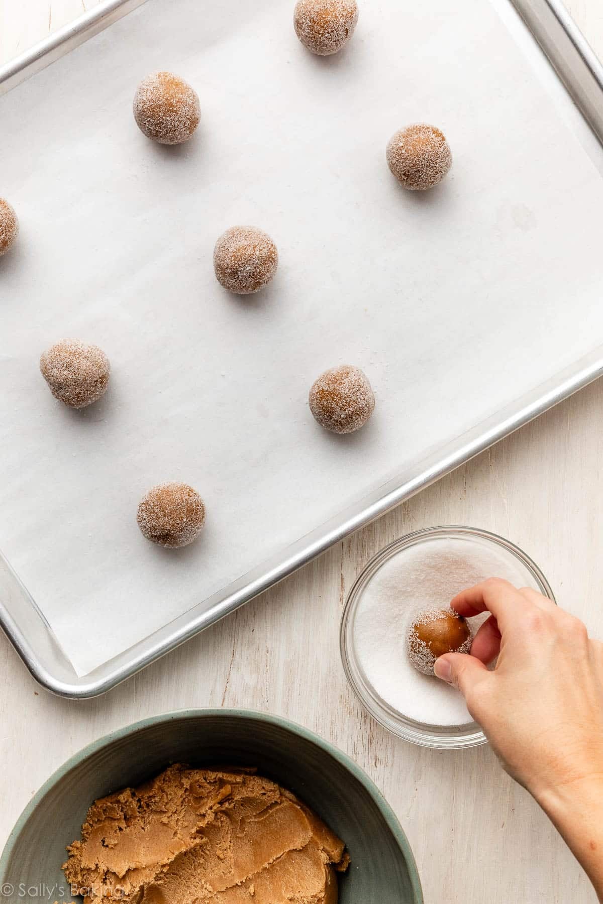 rolling dough balls in bowl of sugar.