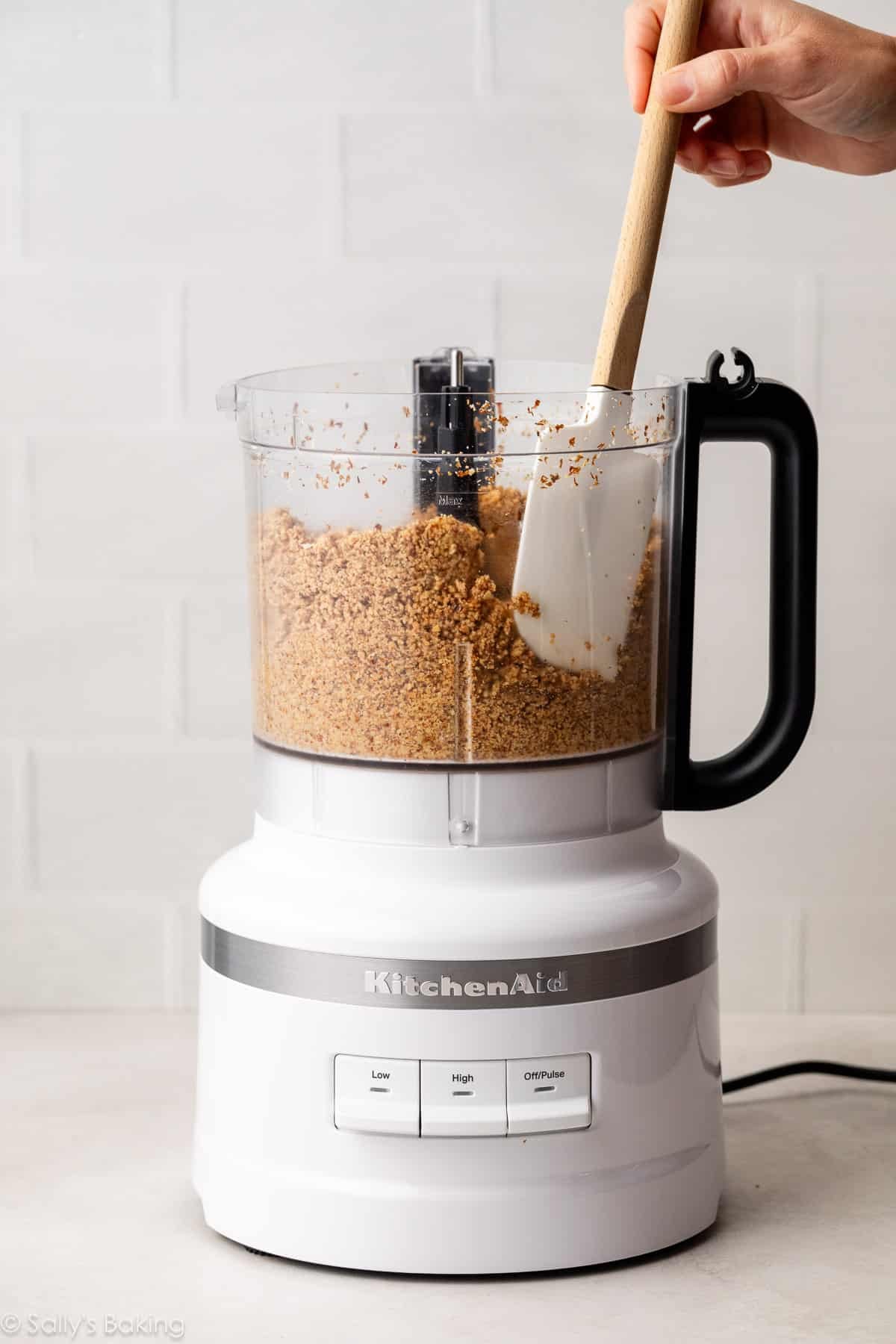 spatula scraping down sides of food processor bowl.
