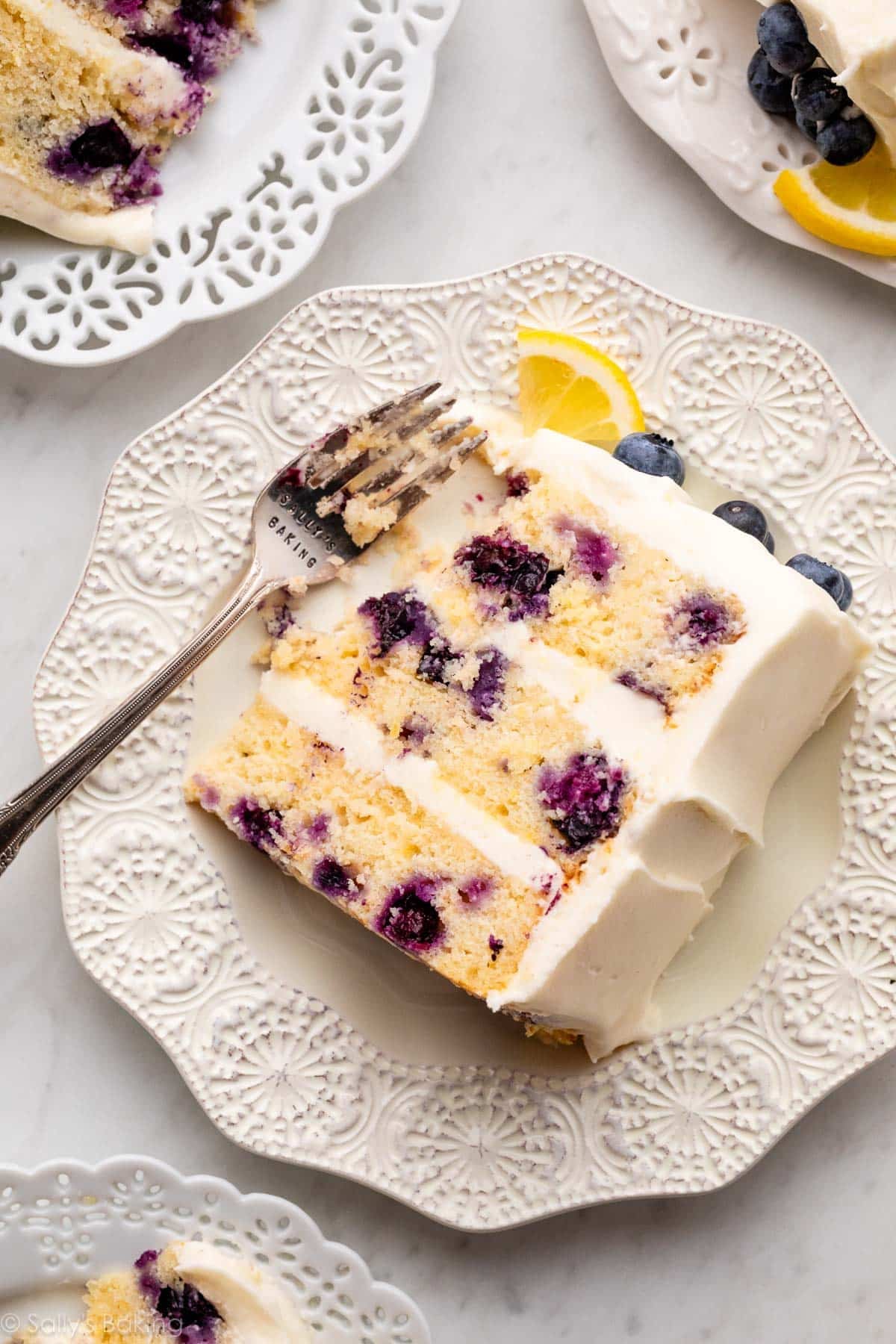 slice of lemon blueberry layer cake on white plate with fork.