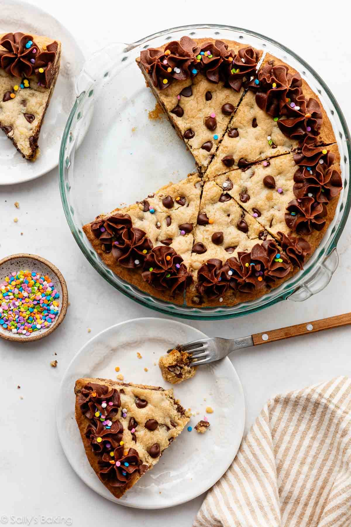chocolate chip cookie cake in glass pie dish and slices on white plates.
