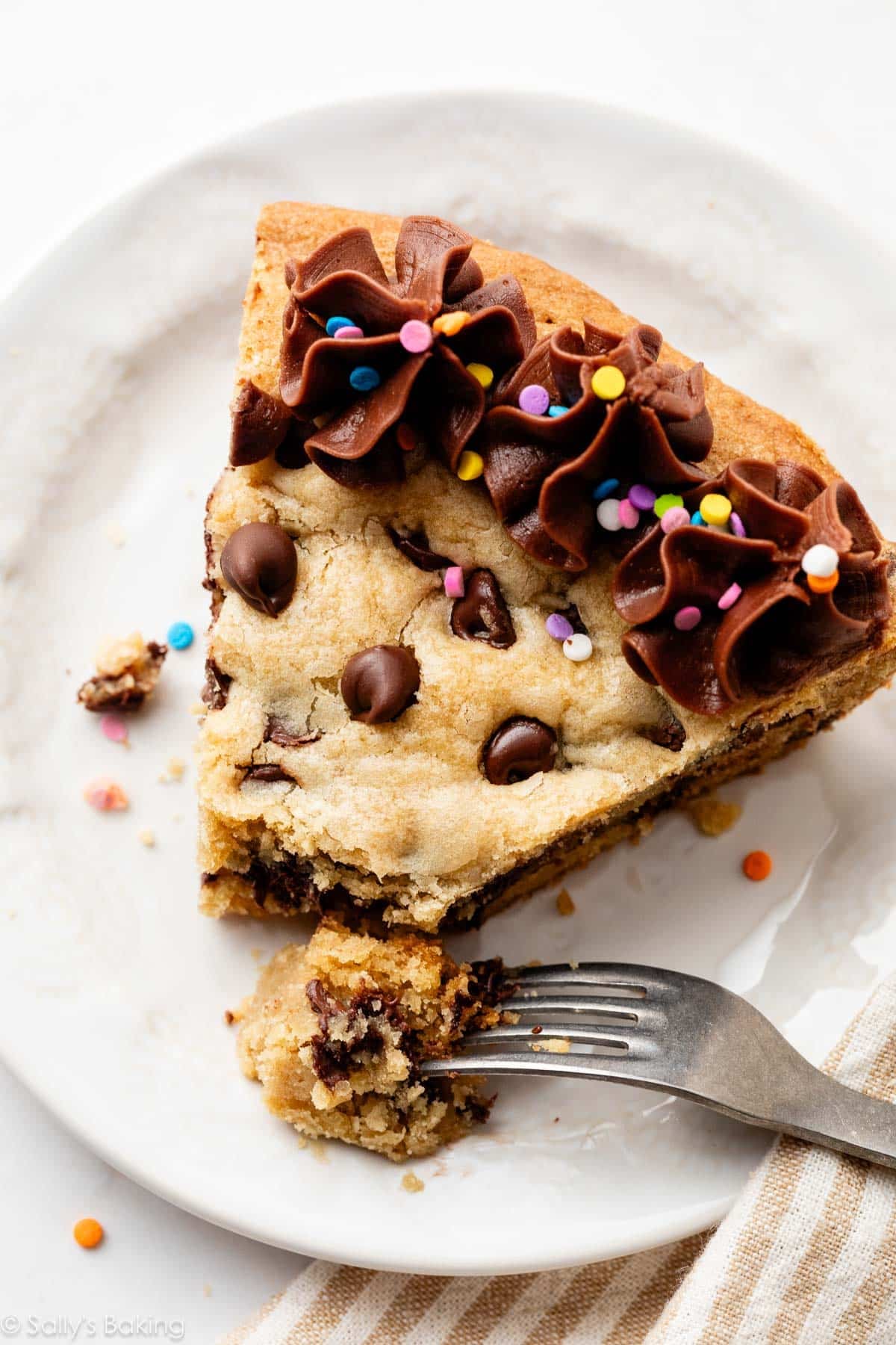 slice of chocolate chip cookie cake on white plate with fork.