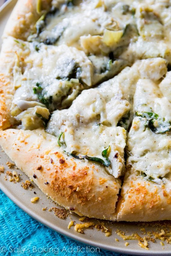 sliced spinach artichoke pizza on a pizza pan