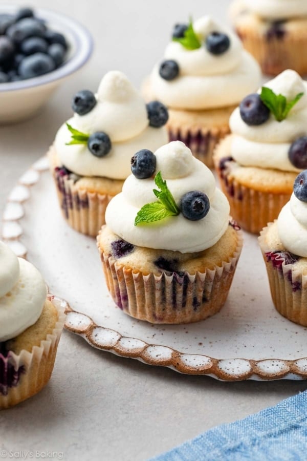 blueberry cupcakes with whipped cream cheese frosting on top with fresh mint.