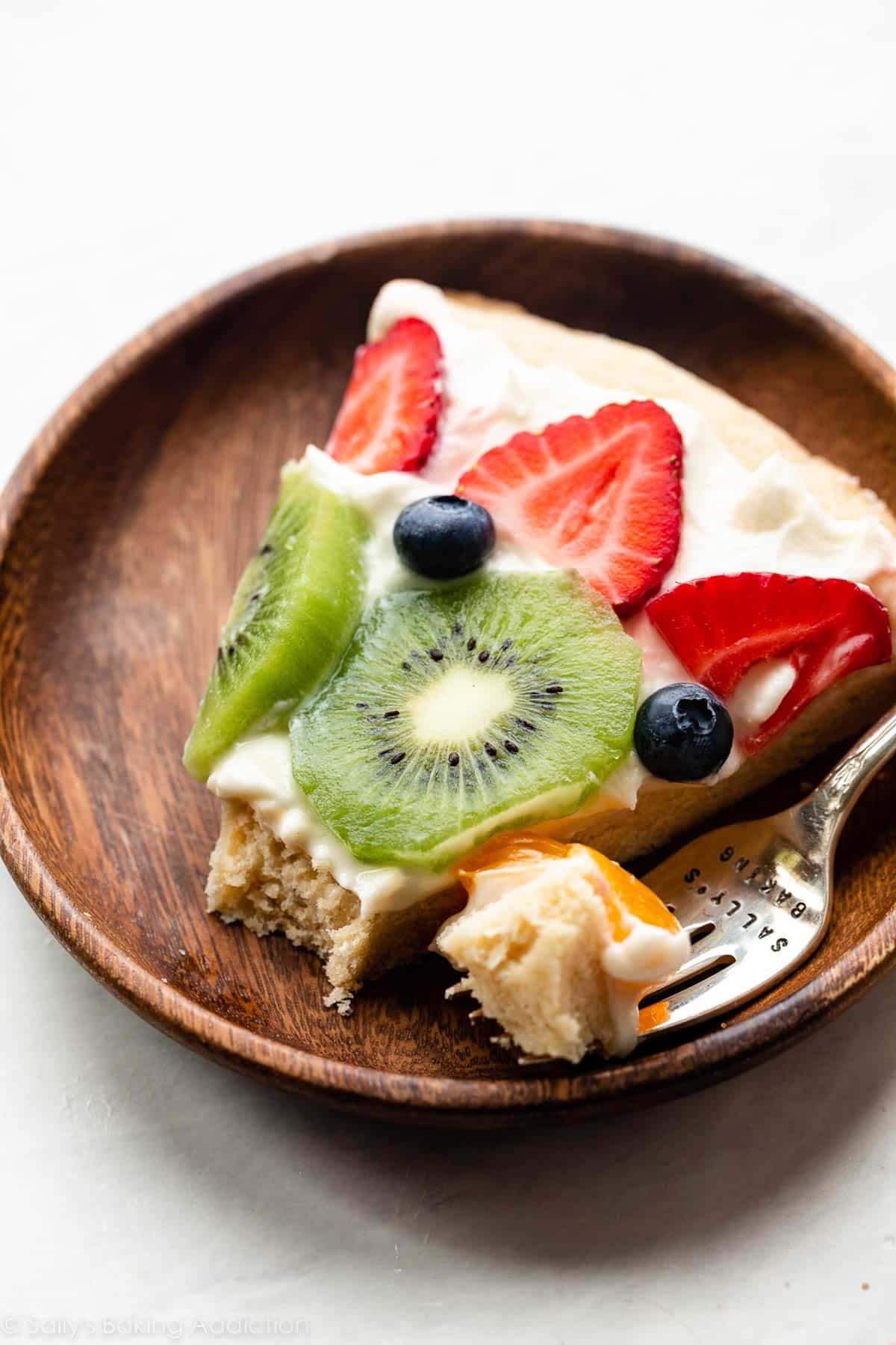 slice of fruit pizza on wooden plate