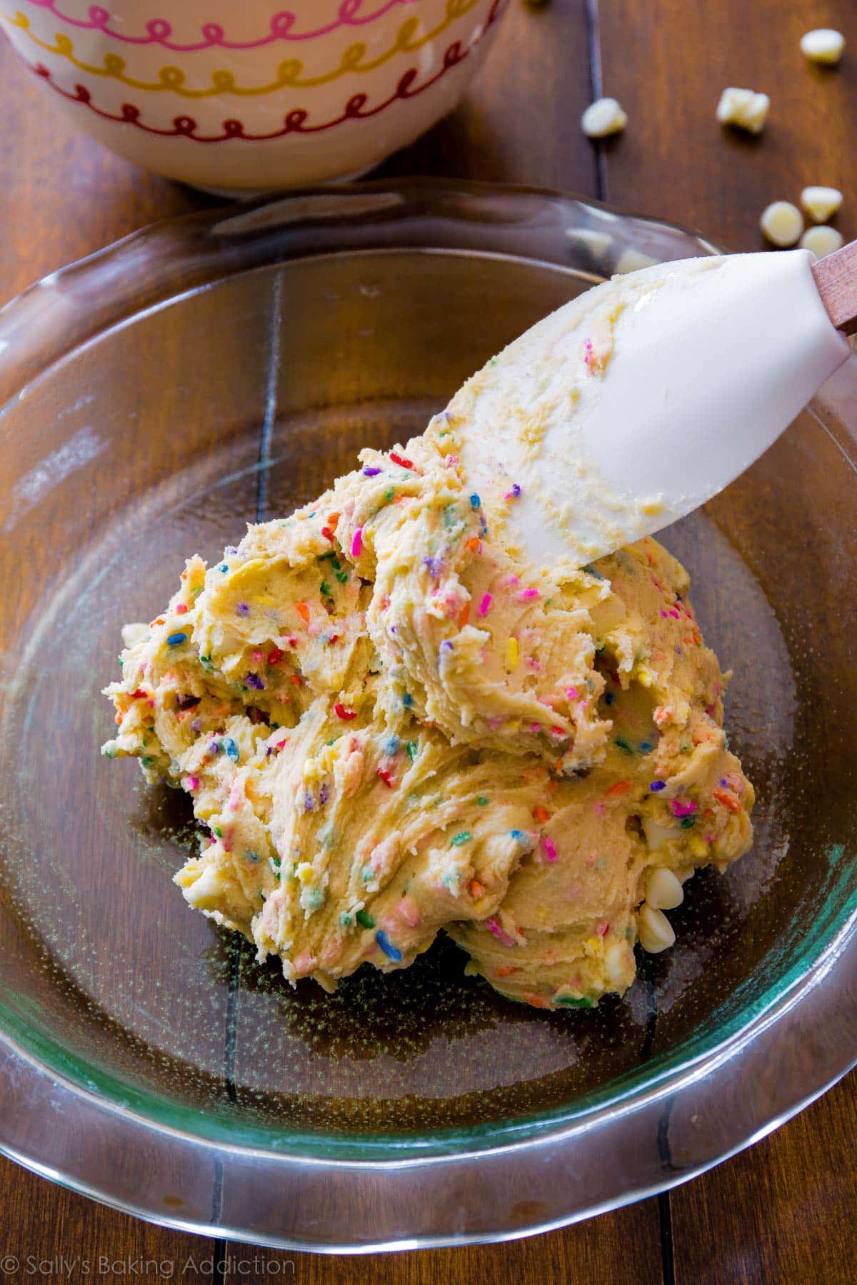 spreading funfetti sugar cookie dough into a round glass baking dish