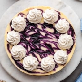 blueberry swirl cheesecake with whipped cream piped on top.
