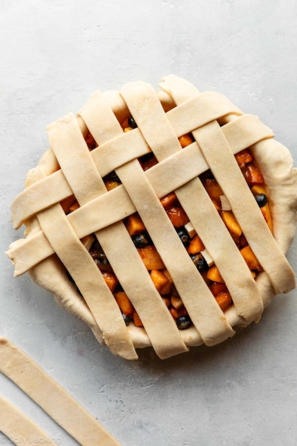 latticing pie dough strips on top of a pie.