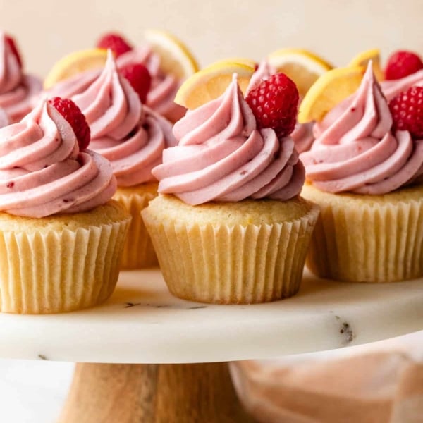 lemon raspberry cupcakes on marble cake stand.