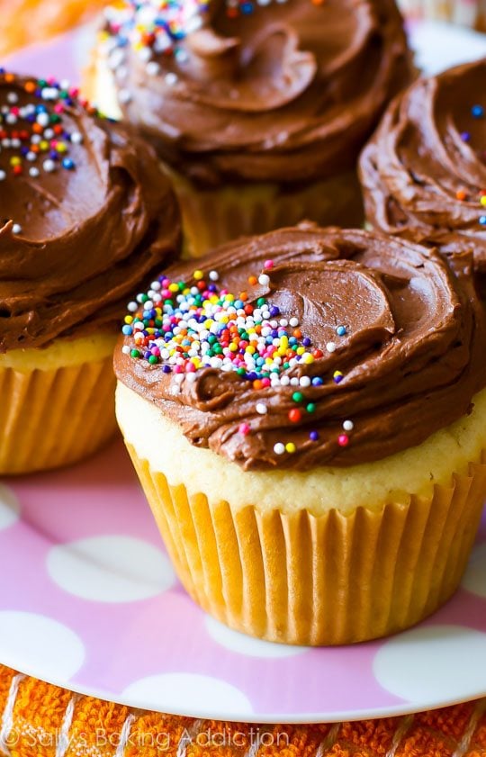 yellow cupcakes topped with milk chocolate frosting and sprinkles