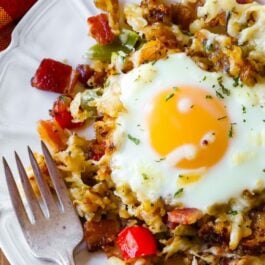 overhead image of crispy hash breakfast skillet on a white plate with a fork