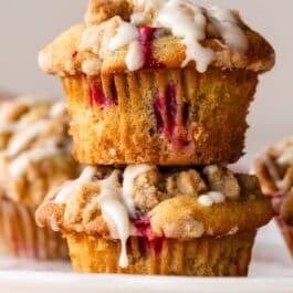 stack of 2 cranberry crumb orange muffins with icing on top.