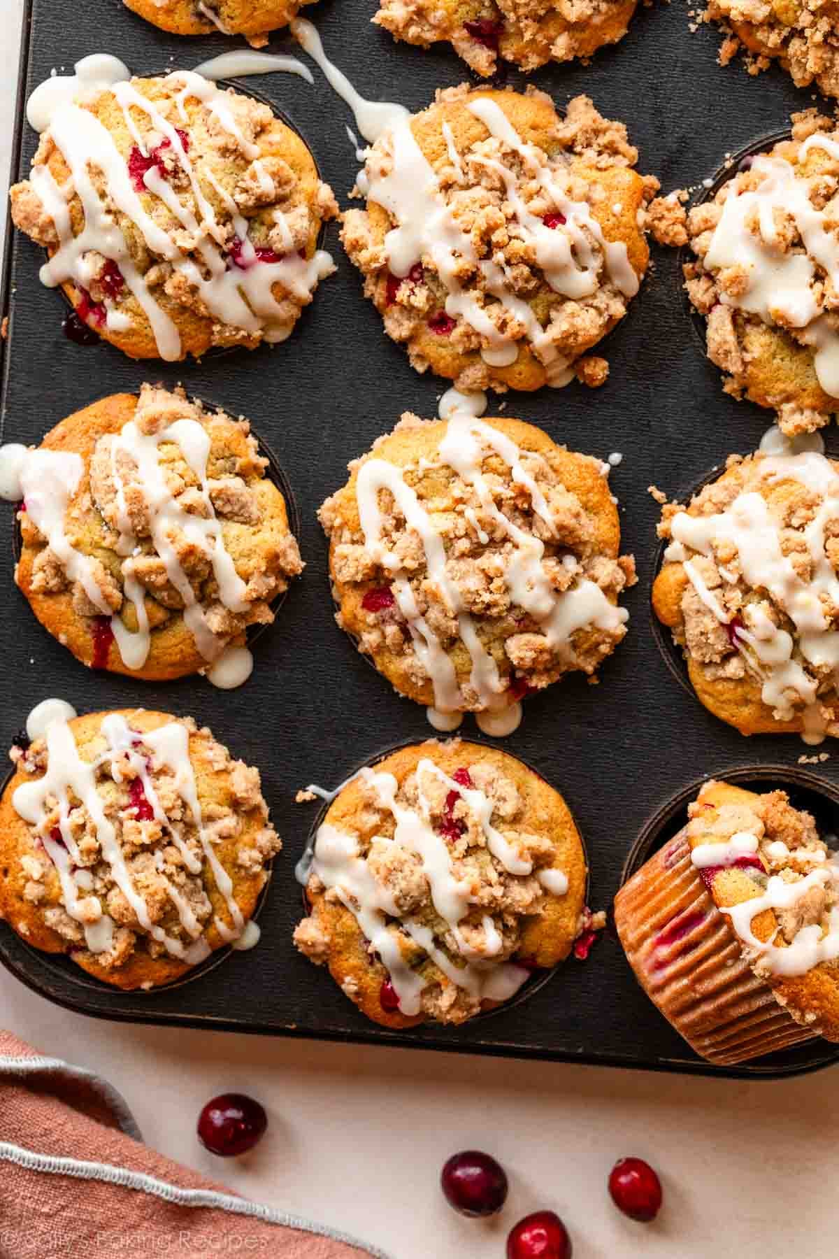 cranberry orange muffins with crumb topping and icing pictured in muffin pan.
