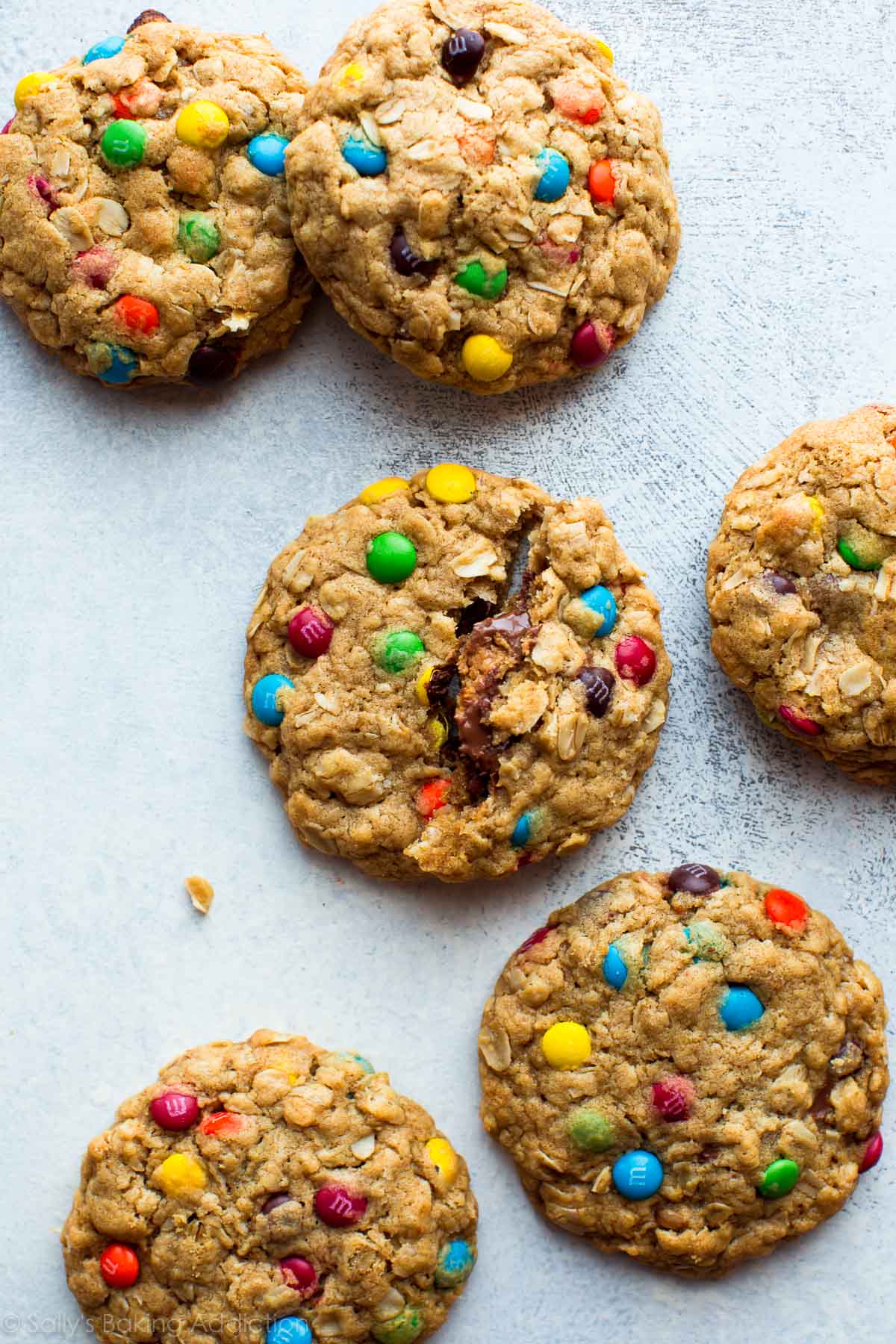 overhead image of monster cookies with one cookie broken in half showing a peanut butter cup inside