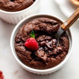 chocolate fudge cake in ramekin with raspberry on top.