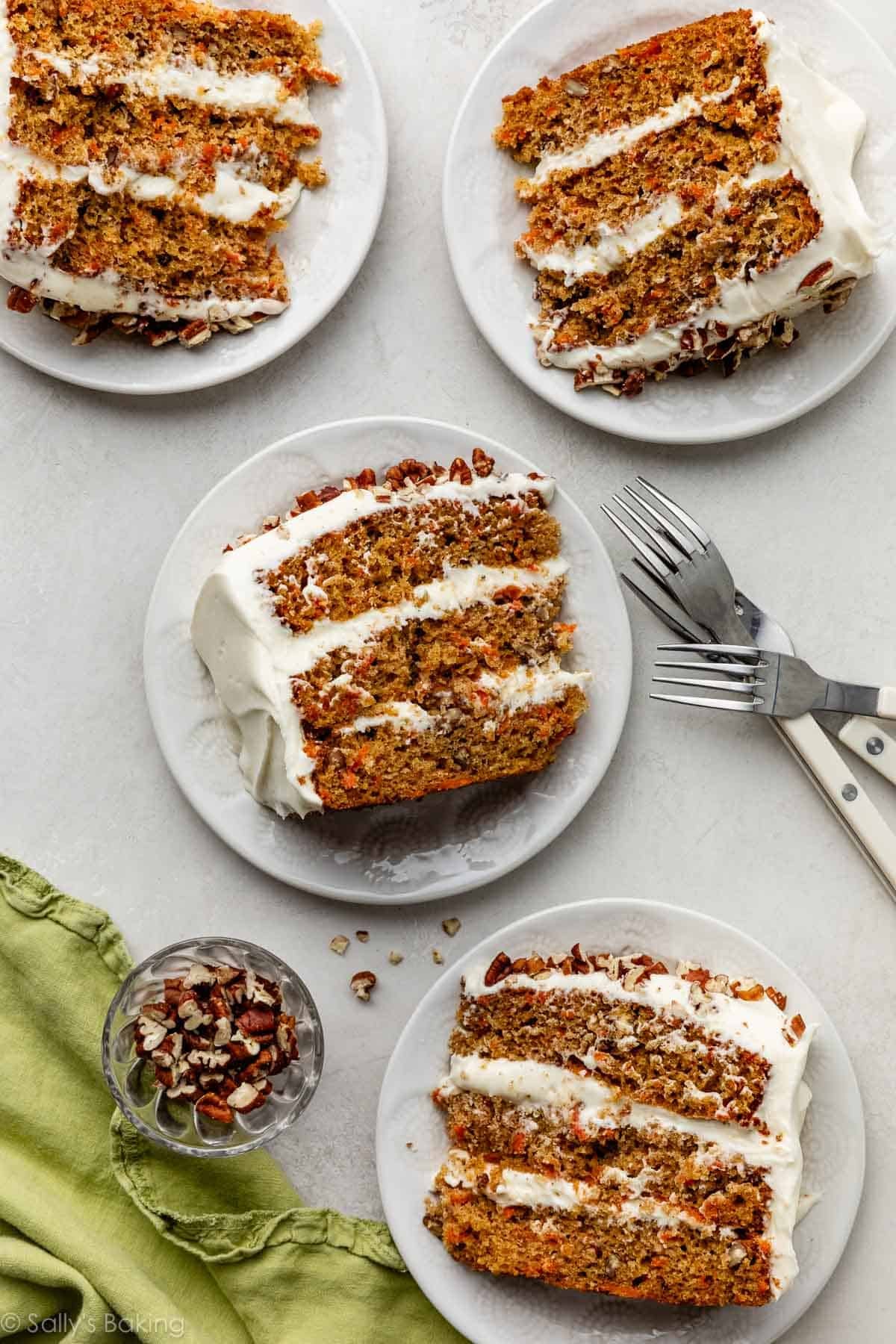slices of carrot cake on white plates with green linen.