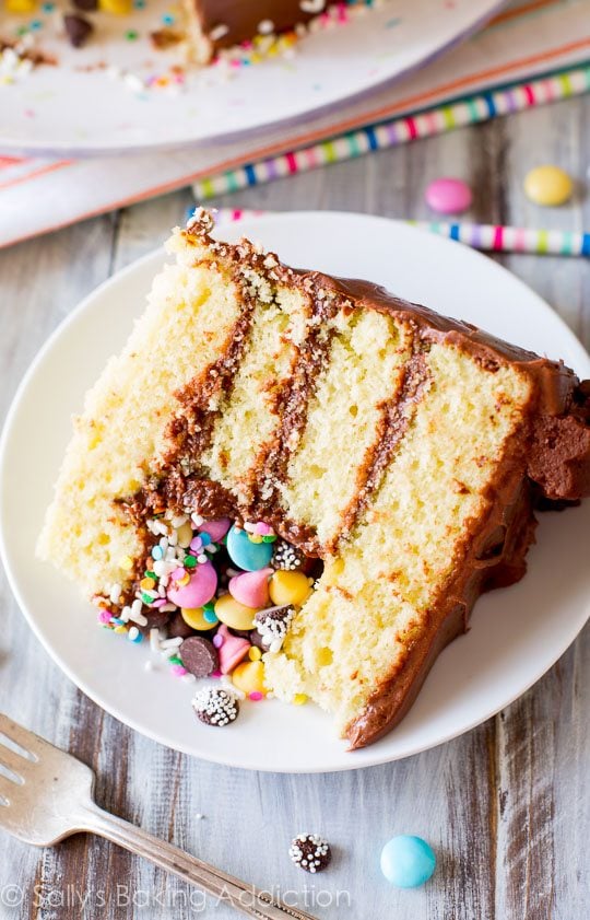 slice of piñata cake on a white plate with a fork
