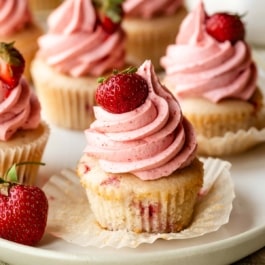 strawberry cupcakes with naturally flavored strawberry buttercream with a fresh strawberry on top.