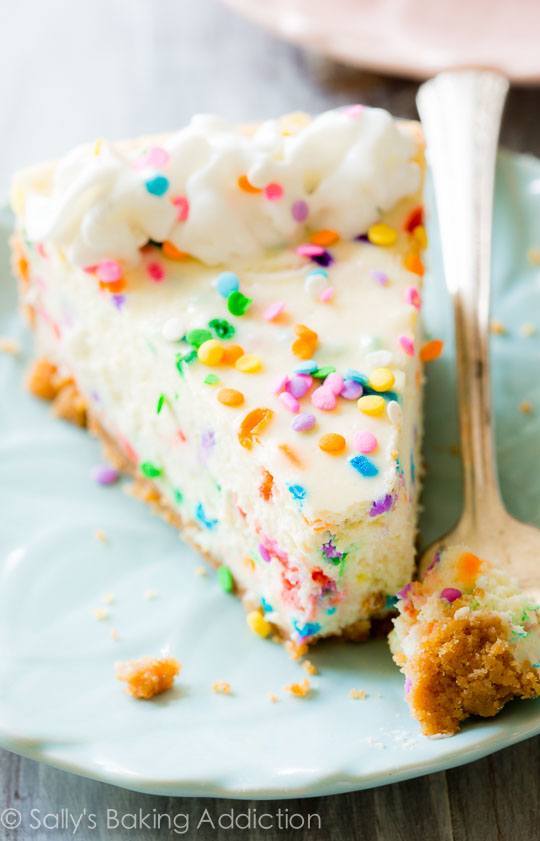 slice of funfetti cheesecake on a blue plate with a fork