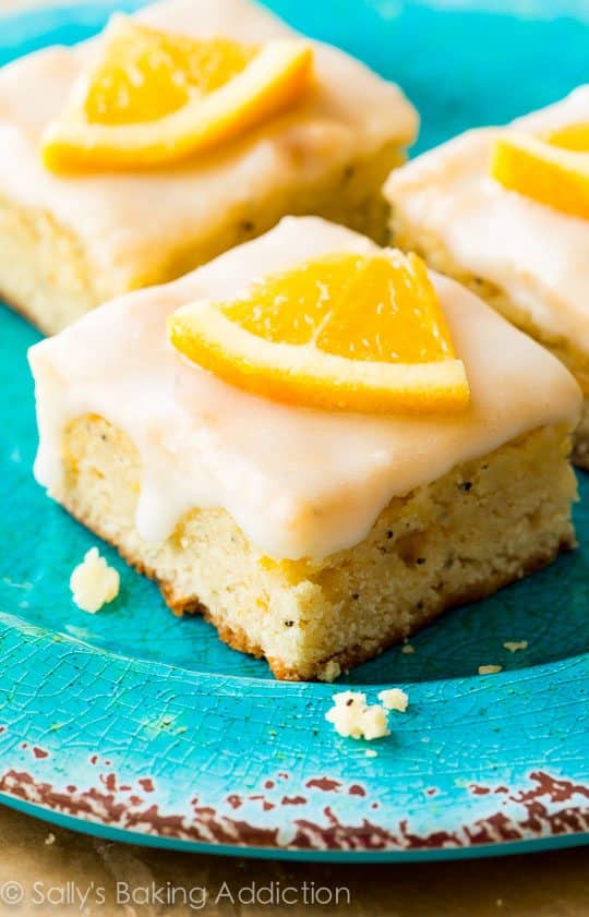 glazed orange poppy seed bars on a blue plate