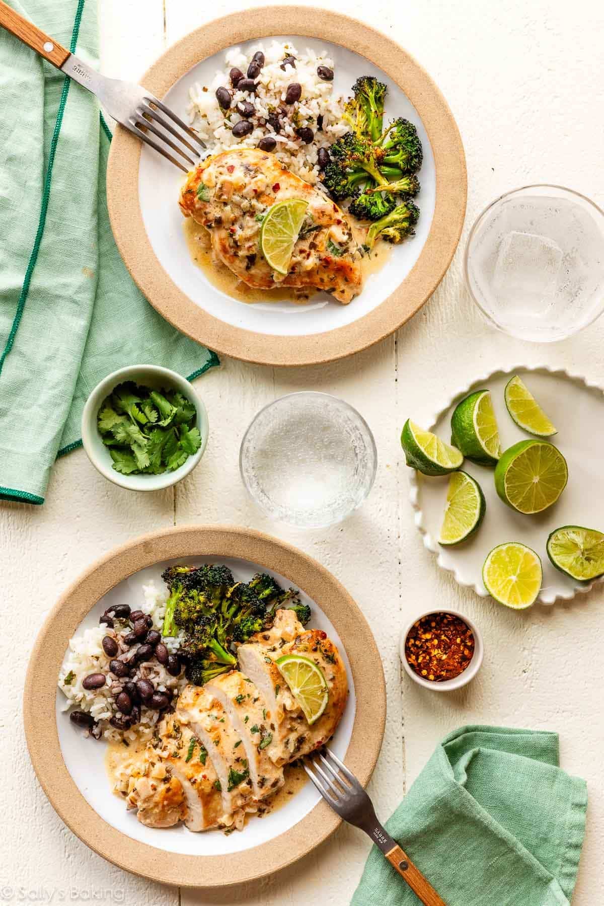 plates of cilantro lime chicken with fresh limes, roasted broccoli, and beans and rice.