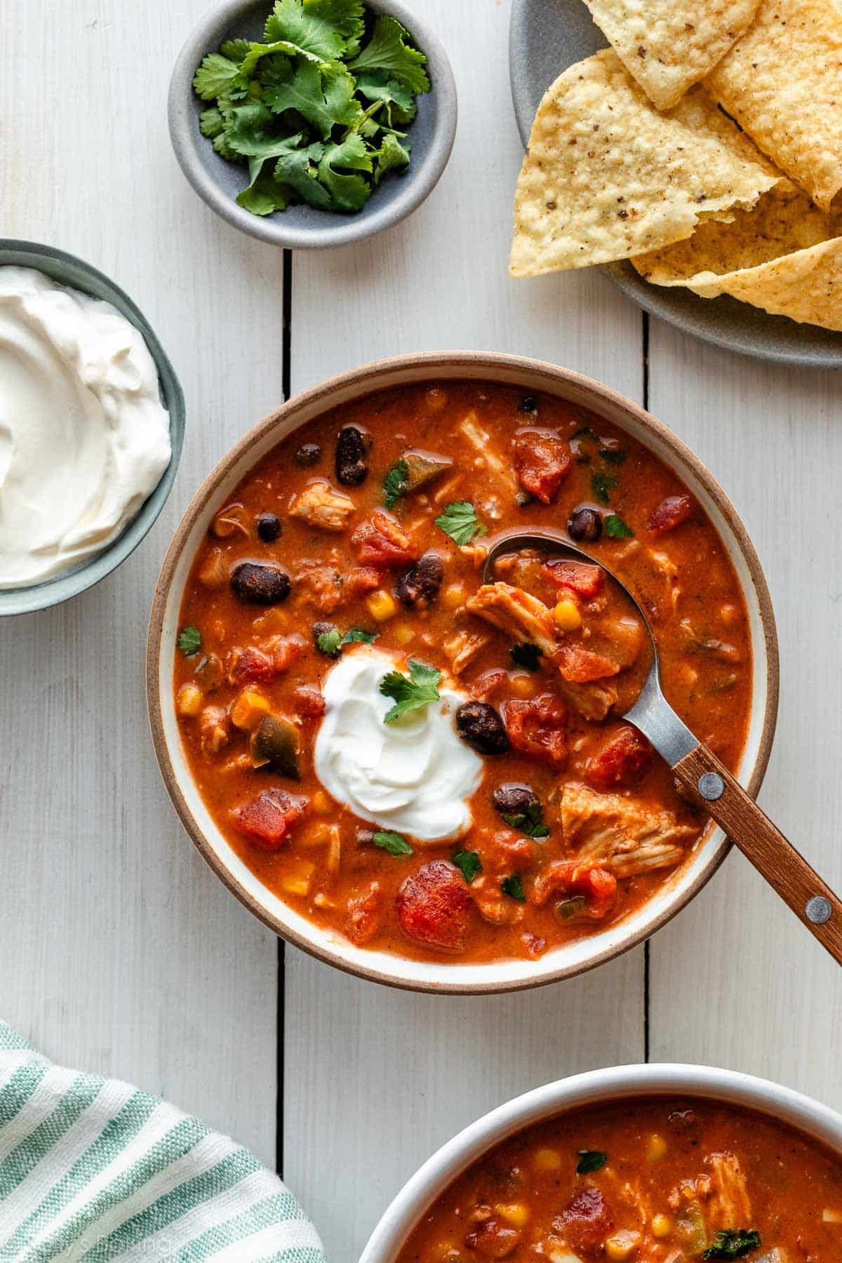 bowl of chicken chili with sour cream and cilantro on top.