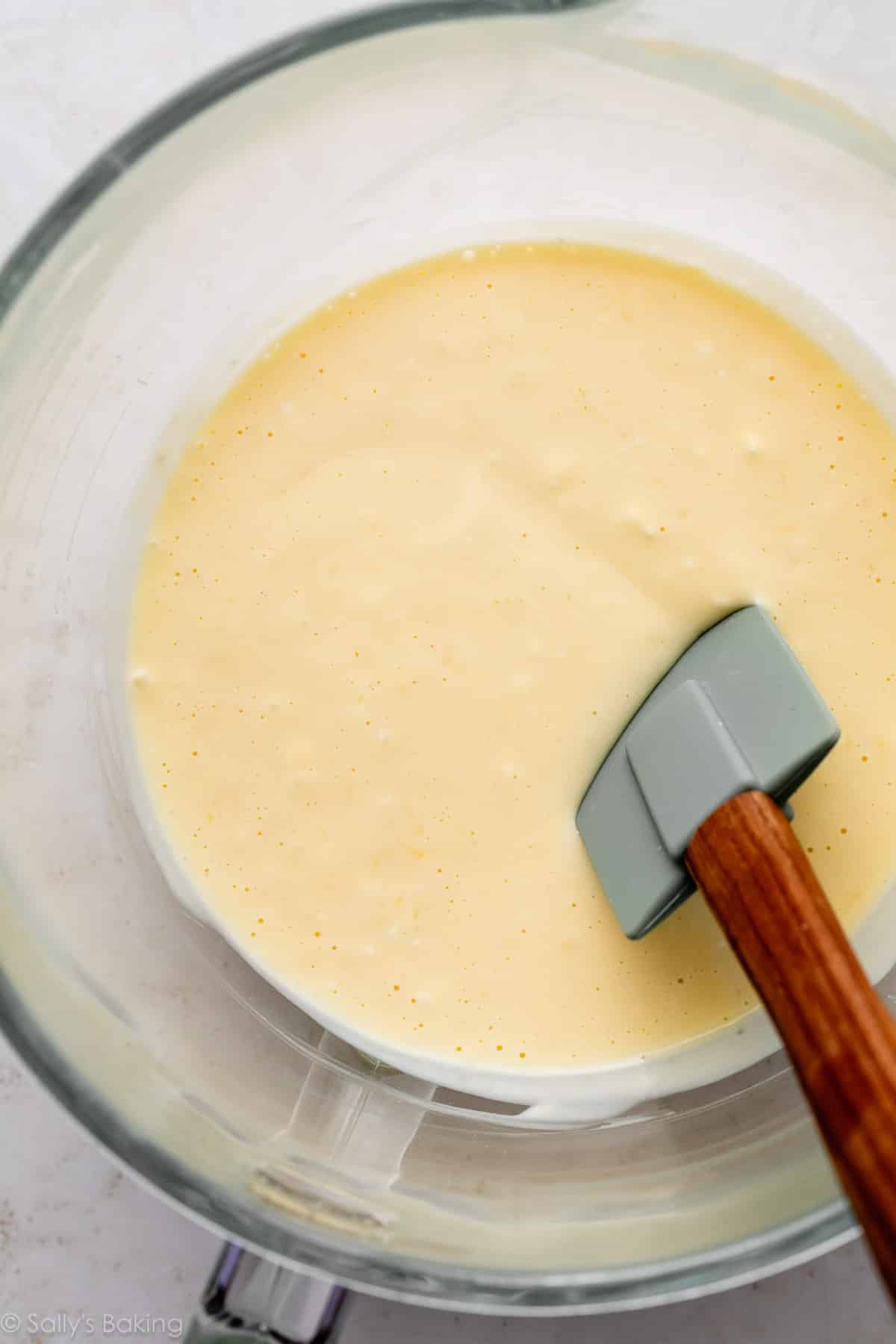 creamy batter in glass bowl with blue-green silicone spatula.