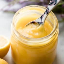 Lemon curd in a glass jar with spoon