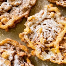 overhead image of funnel cakes topped with confectioners' sugar