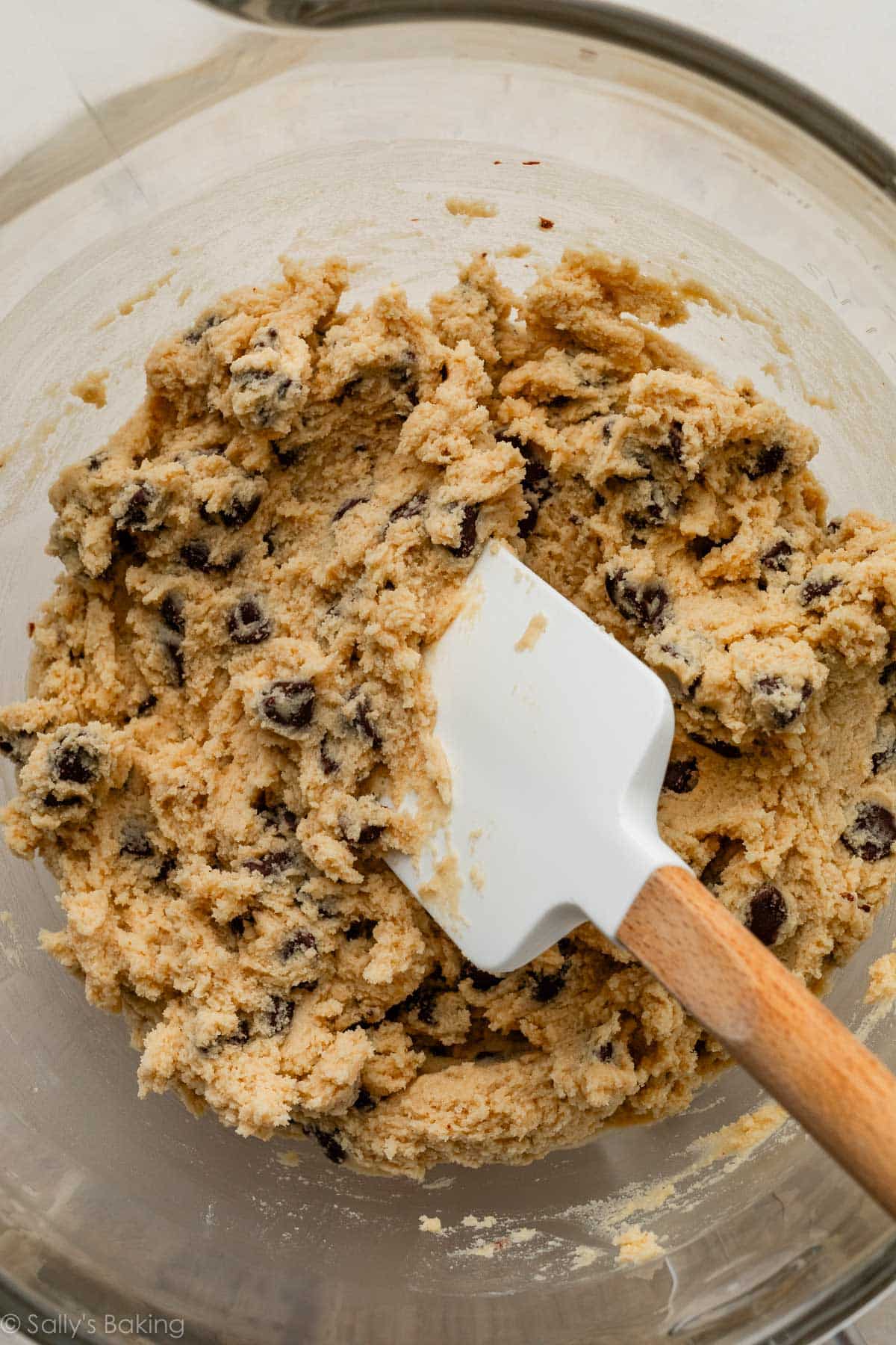 cookie dough in glass bowl with white spatula.
