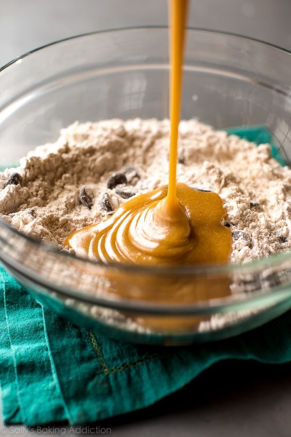 pouring wet ingredients into dry ingredients in a glass bowl
