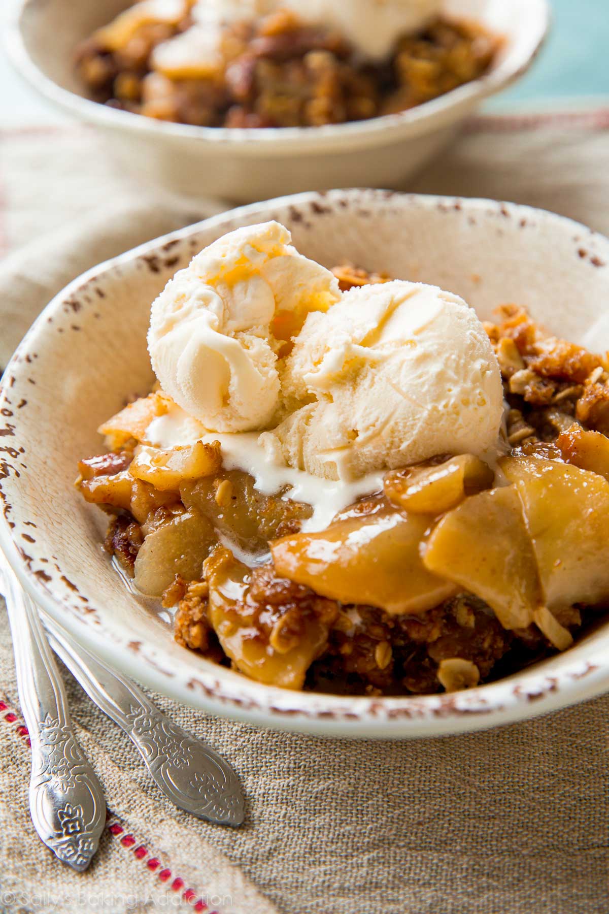 serving of apple pear crisp in a white bowl with a scoop of vanilla ice cream on top