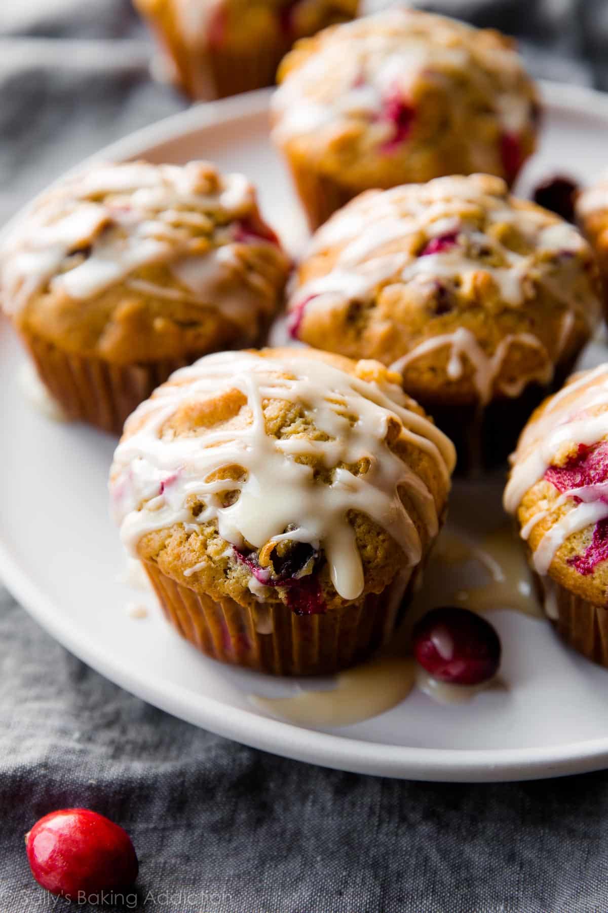 cranberry cardamom spice muffins with orange icing on a white plate