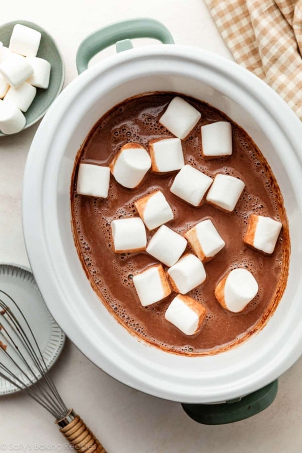 homemade hot chocolate drink in slow cooker with marshmallows floating on top.