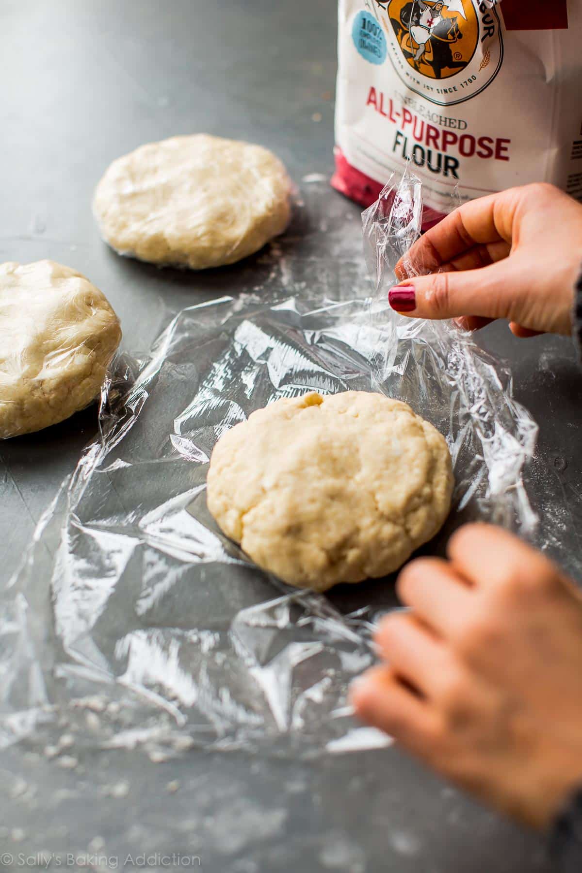 hands wrapping up a disc of rugelach cookie dough