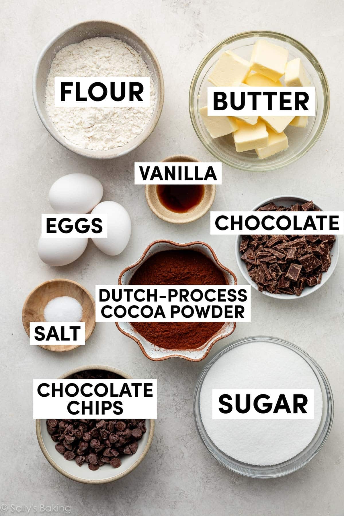 ingredients in bowls including sugar, chocolate chips, butter, flour, eggs, and vanilla.