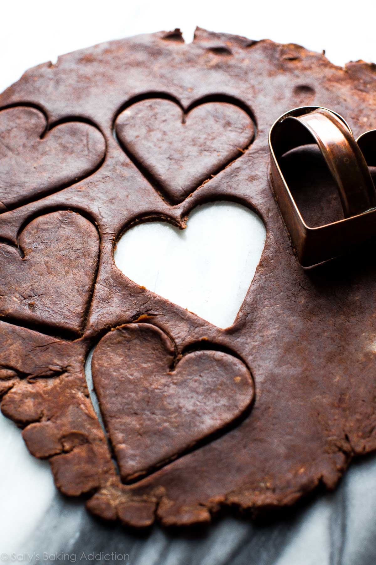 chocolate pie dough rolled out with a heart cookie cutter