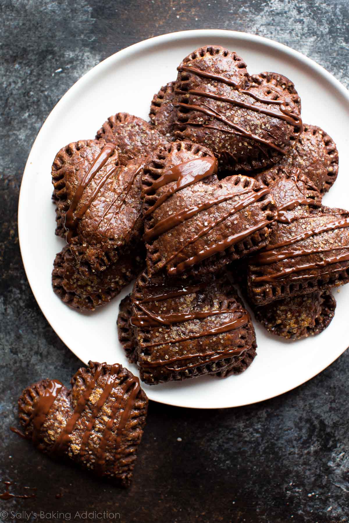 heart shaped chocolate hand pies drizzled with chocolate topping on a white plate