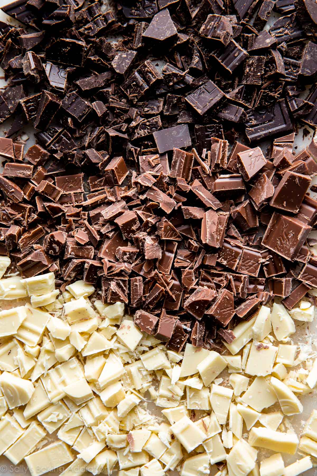chopped white chocolate, milk chocolate, and dark chocolate on a cutting board