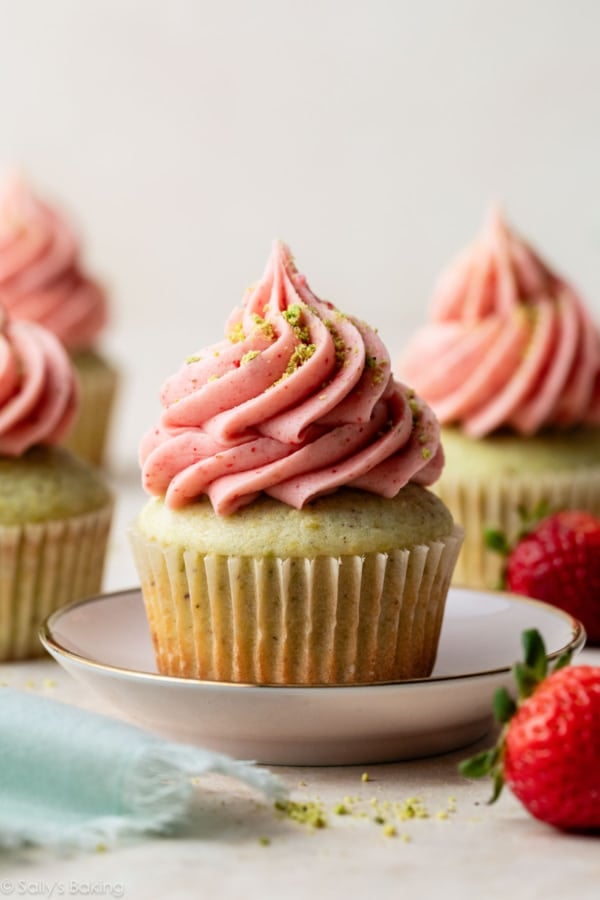 pistachio cupcake with strawberry buttercream piped on top.