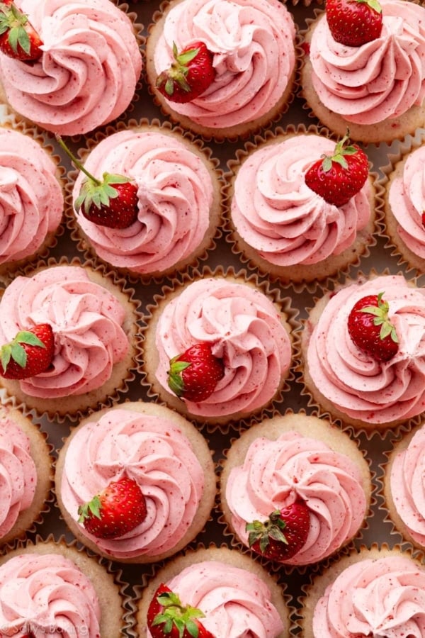 strawberry cupcakes with strawberry buttercream and fresh strawberry on top.