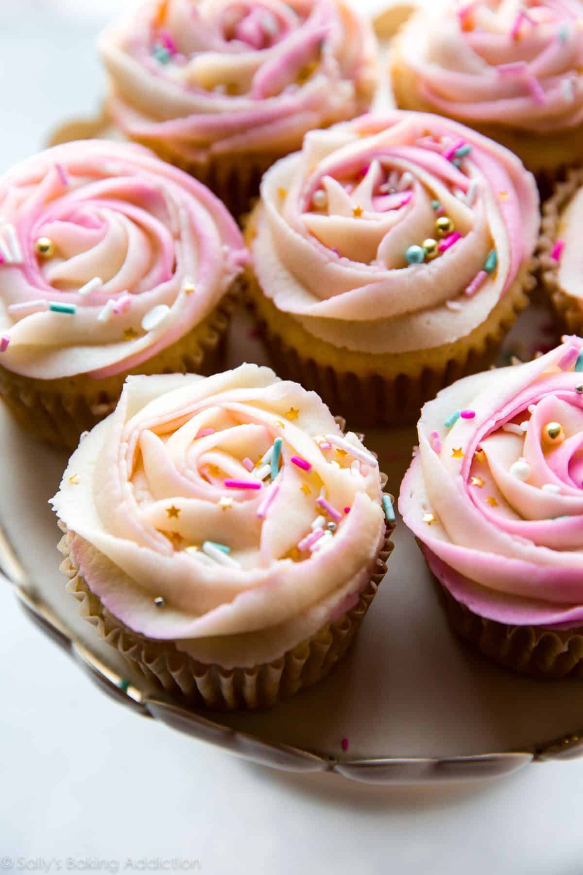 cupcakes with pink frosting roses on top on a cake stand
